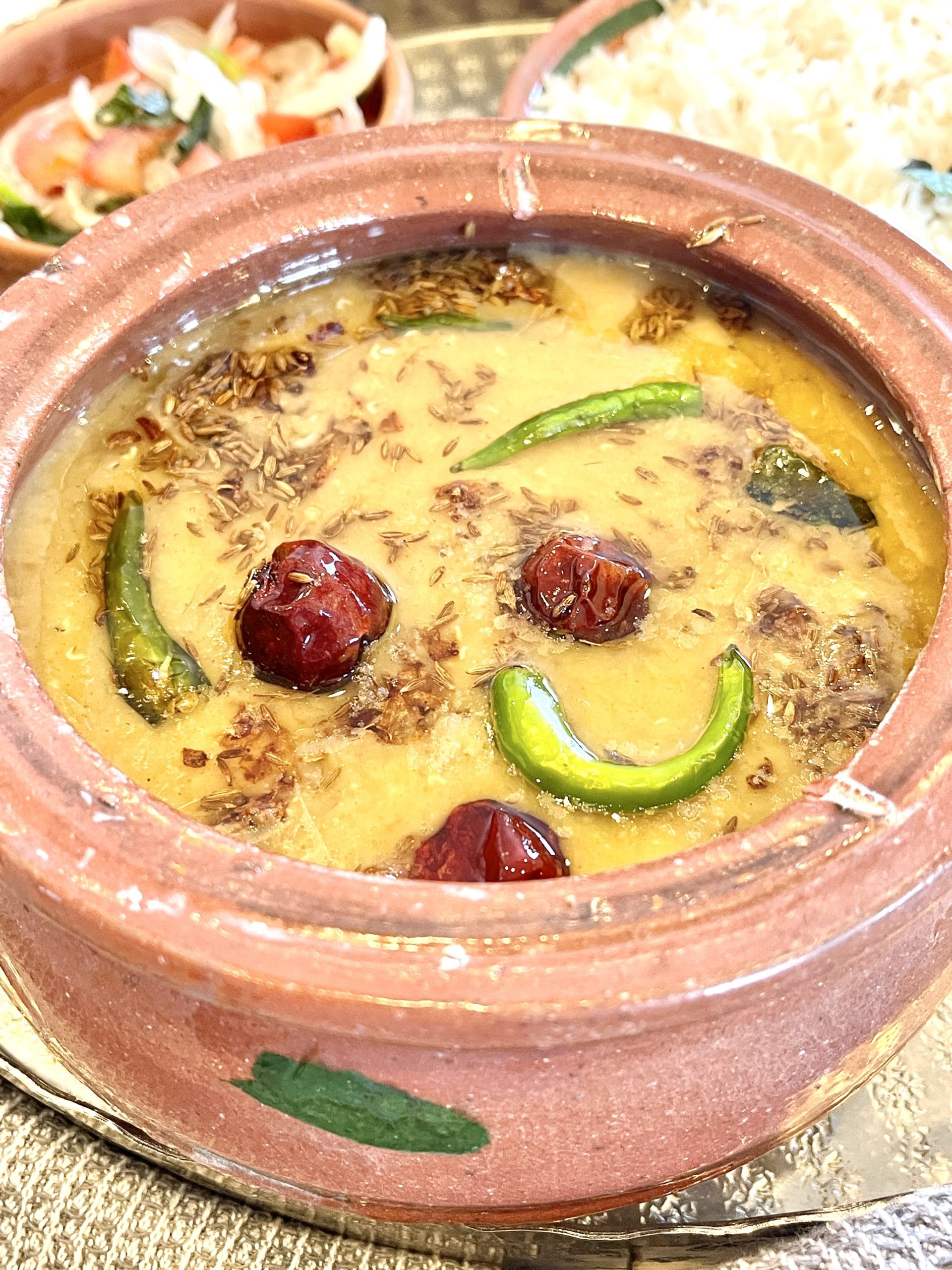 Masoor Dal served in a clay bowl topped with garlic tarka and chilies