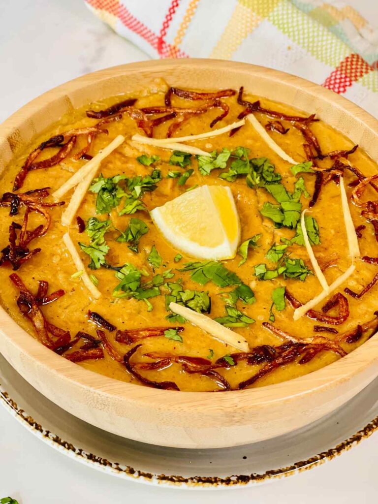 Chicken Haleem garnish with mint and ginger and served with lemon wedges.