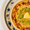 In a bowl, chicken rashi dar haleem is served with fried onion and julian cut
