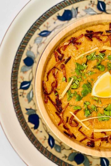 In a bowl, chicken rashi dar haleem is served with fried onion and julian cut