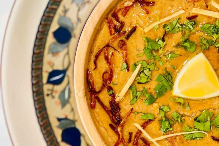 In a bowl, chicken rashi dar haleem is served with fried onion and julian cut