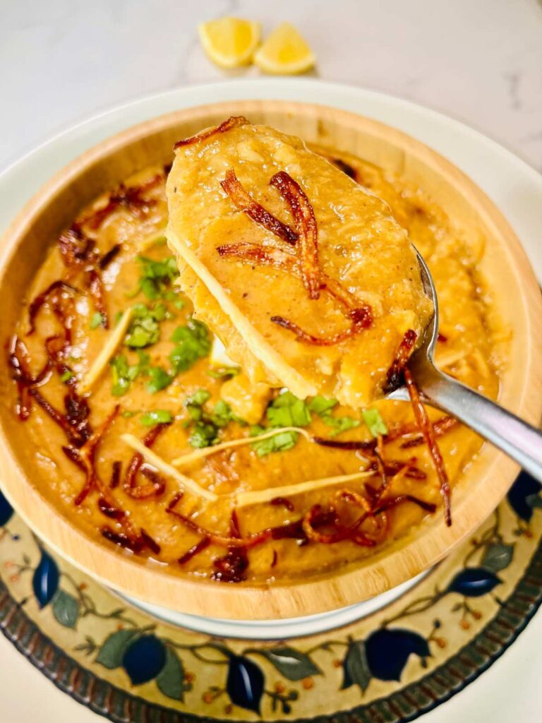 In a bowl, chicken rashi dar haleem is served with fried onion and julian cut ginger.